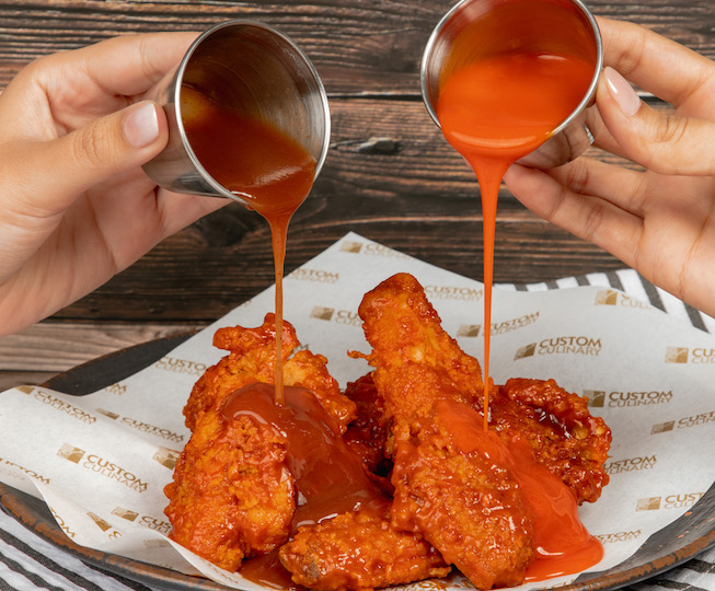 hot buffalo wings with sauce pouring on top